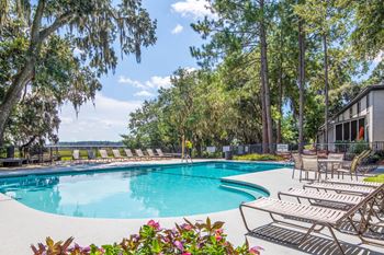 Marsh Cove Apartments in Savannah Georgia photo of a swimming pool with chaise lounge chairs and trees